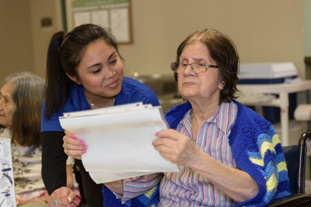 Proveer at Northgate | Memory care resident reading papers alongside associate