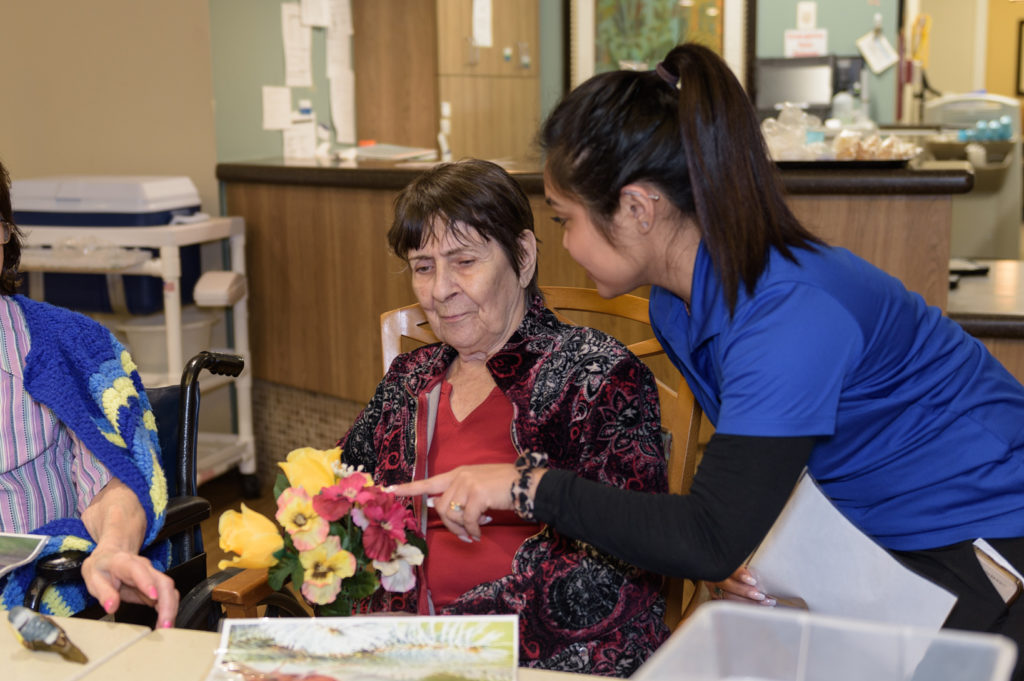 Proveer at Northgate | Memory care resident holding flowers alongside associate